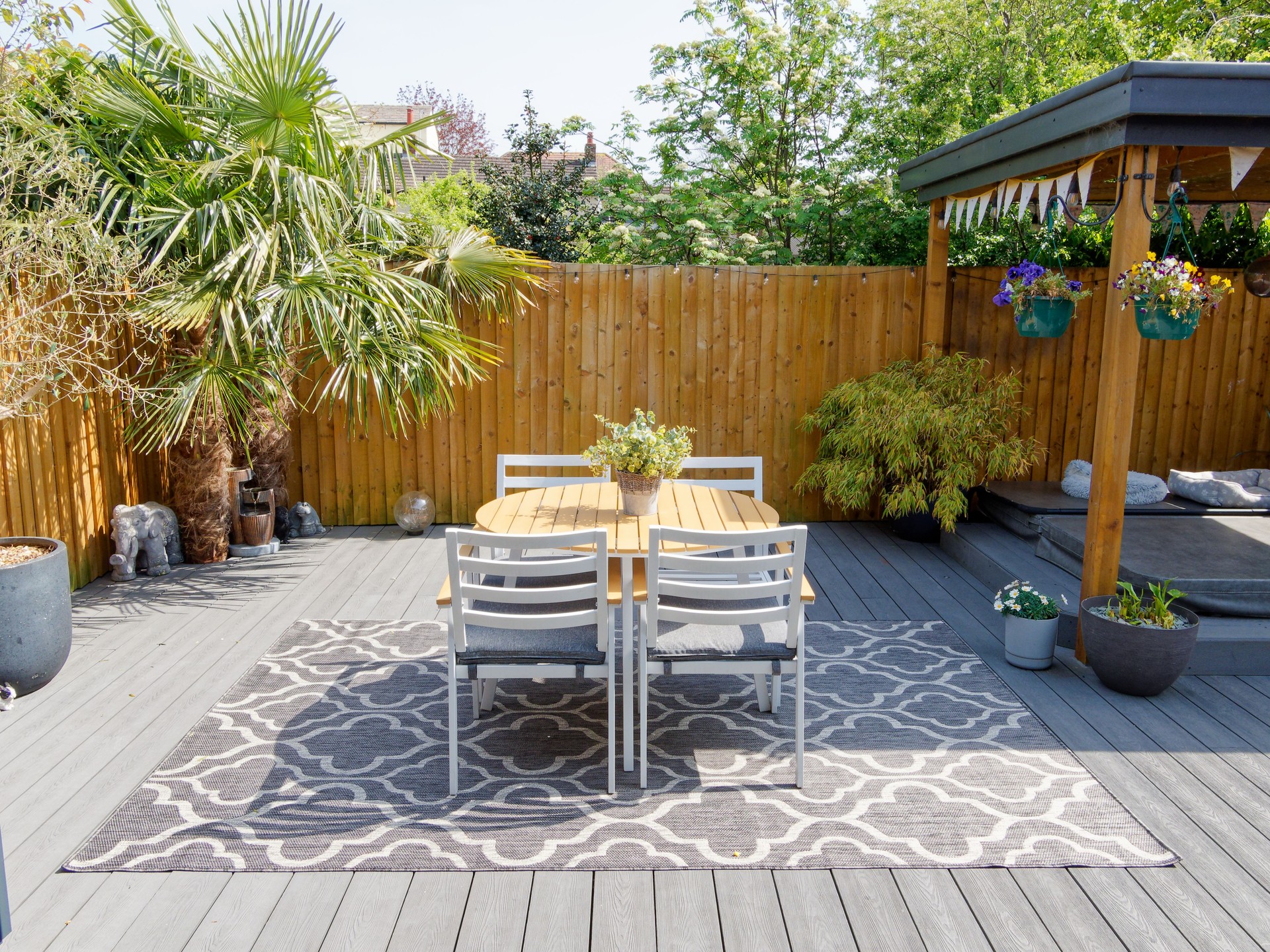Minimalistic English modern garden with table and chairs. Sunny summers day with green plants and decking on the patio