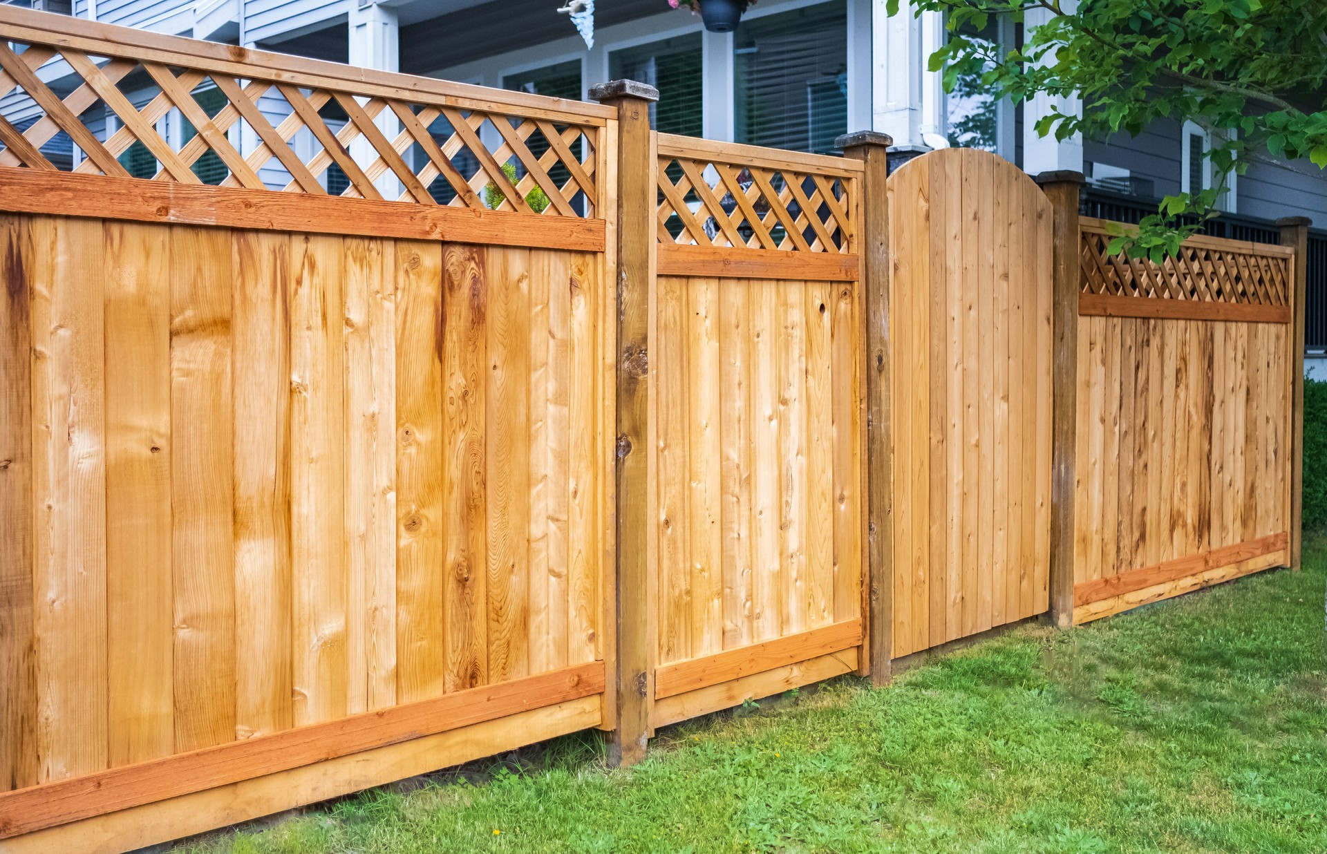 Nice wooden fence around house. Wooden fence with green lawn. Street photo